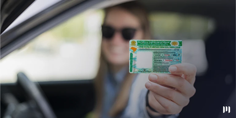 Mulher dentro de um carro mostra sua CNH pela janela para alguém de fora!