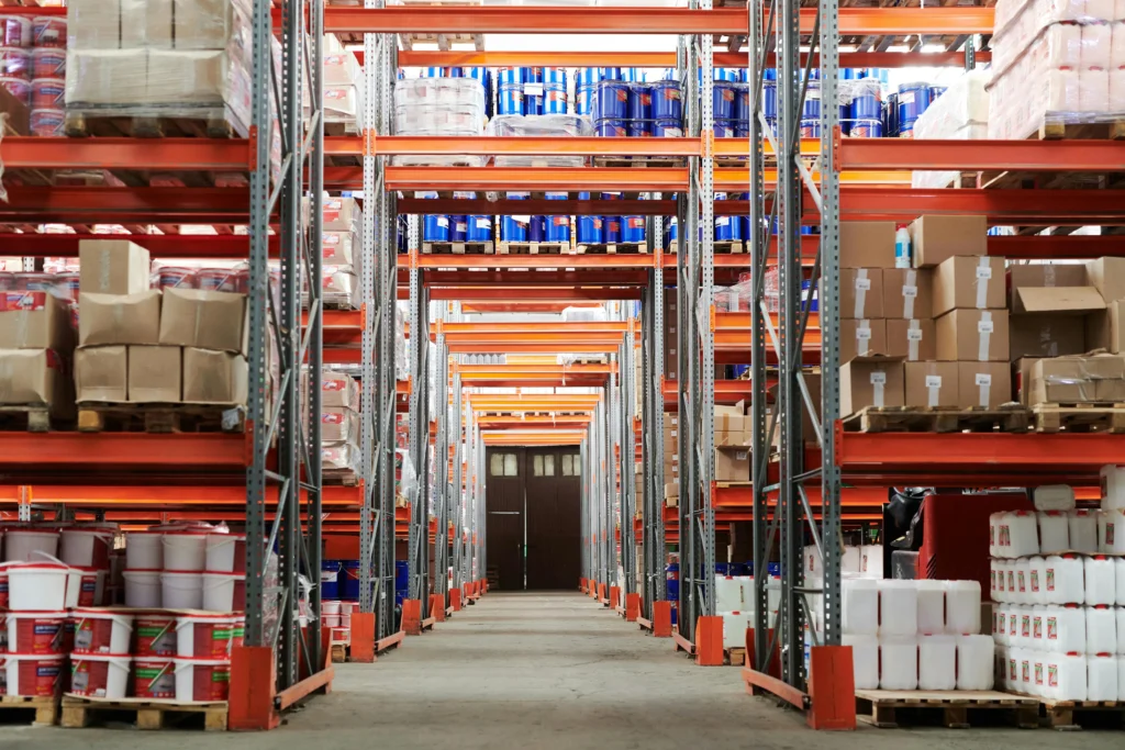 de uma fábrica onde várias estantes gigantes estão repletas de produtos estocados. A imagem remete as novas quotas de depreciação acelerada