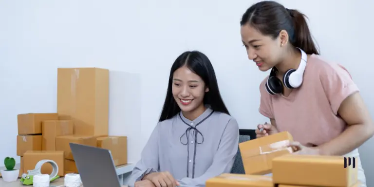 Duas empreendedoras organizam encomendas de uma loja virtual, representando os pequenos negócios beneficiados pelo Prospera MEI.